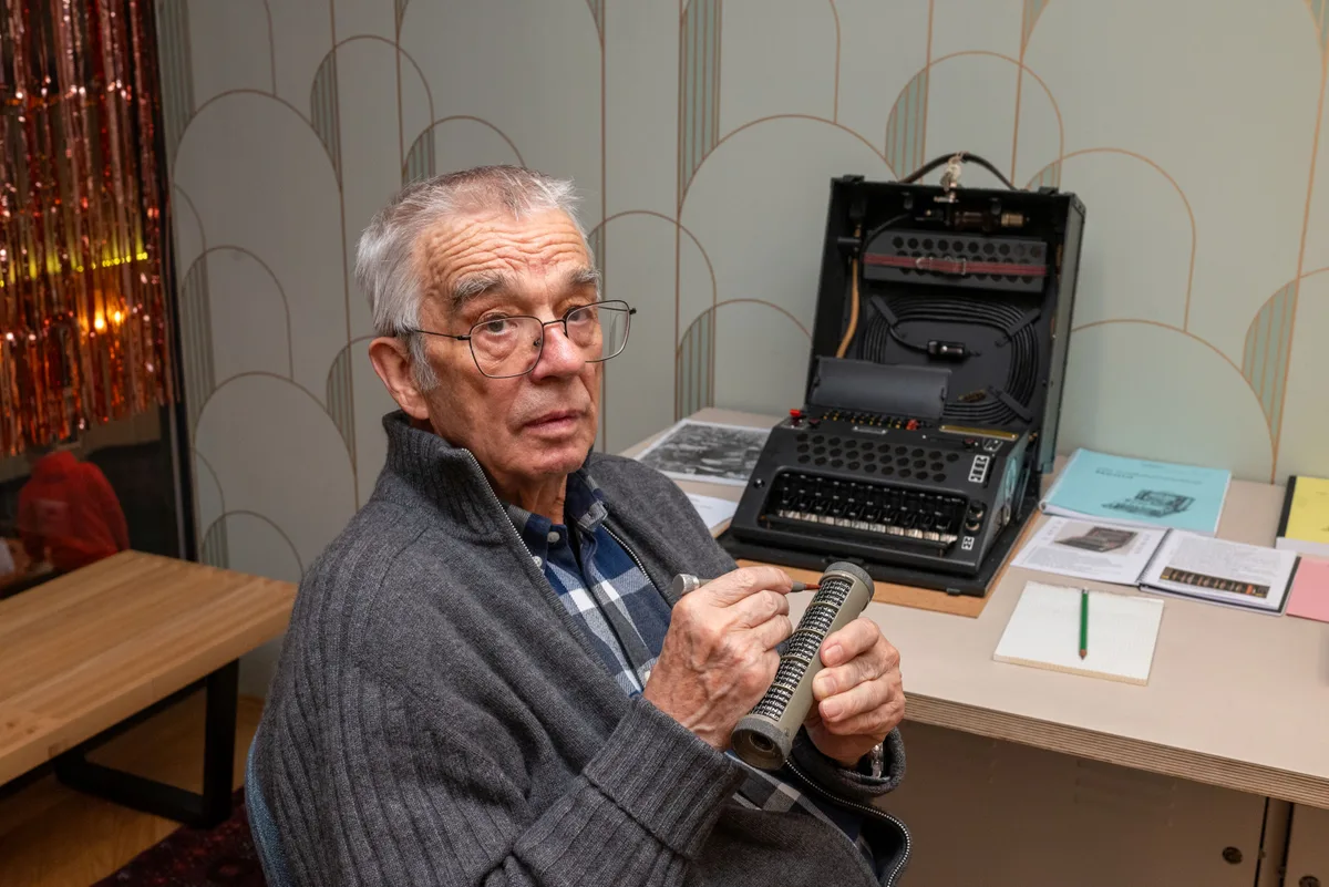 Mann sitzend mit Chiffriermaschine Nema im Hintergrund